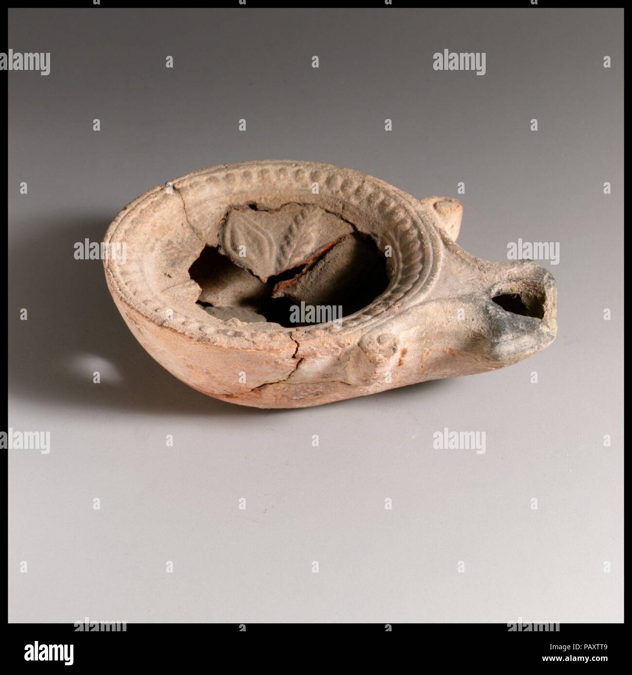 Olio di terracotta con lampada. Cultura: Romano. Dimensioni: 1 3/16 × 3 15/16 in. (3 × 10 cm). Data: 1° secolo a.c.-1st secolo D.C.. Loeschcke tipo 1A. Stampo-fatta. Discus: un rosone con quattro grandi petali, intervallati con frondosi fronde; un unico foro di riempimento al centro, con una banda di puntini in rilievo entro due cerchi a bordo. Volute fiancheggianti ugello angolare, con un grande foro di stoppino. Base rialzata ad anello e una base piana. Rotto e riparato con un foro nel corpo. Museo: Metropolitan Museum of Art di New York, Stati Uniti d'America. Foto Stock