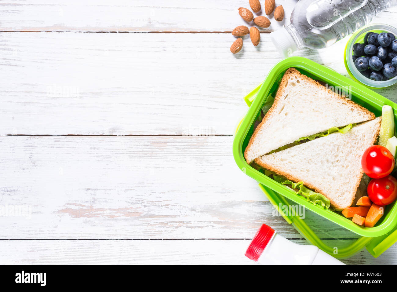 Scatola di pranzo con sandwich, verdure, acqua, noci e bacche. Foto Stock