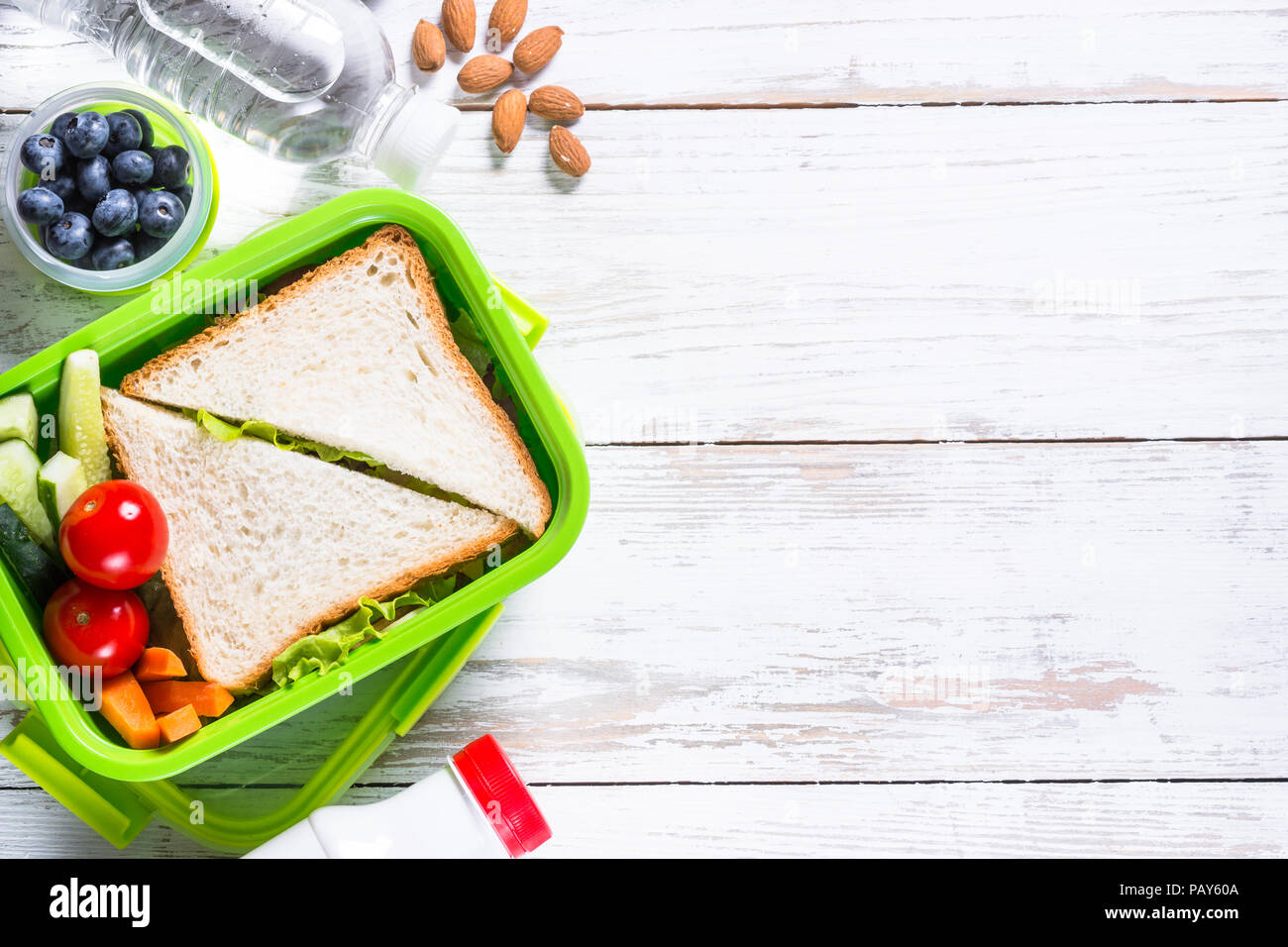 Scatola di pranzo con sandwich, verdure, acqua, noci e bacche. Foto Stock