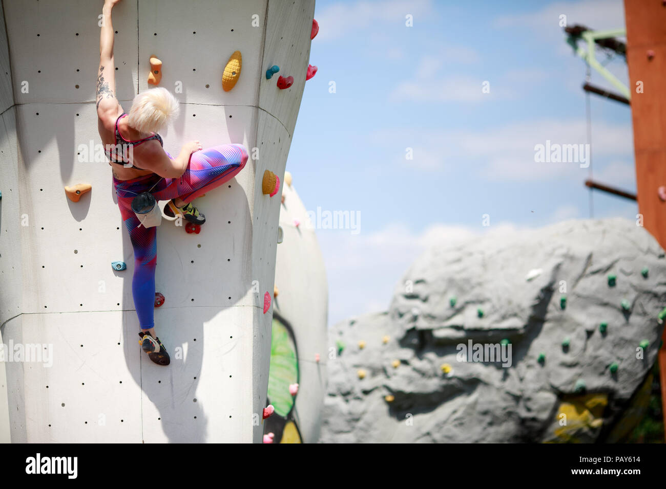 Foto dal retro dello sport donna con capelli corti in abbigliamento  sportivo praticare sulla parete per arrampicata contro il cielo blu con  nuvole durante il giorno Foto stock - Alamy