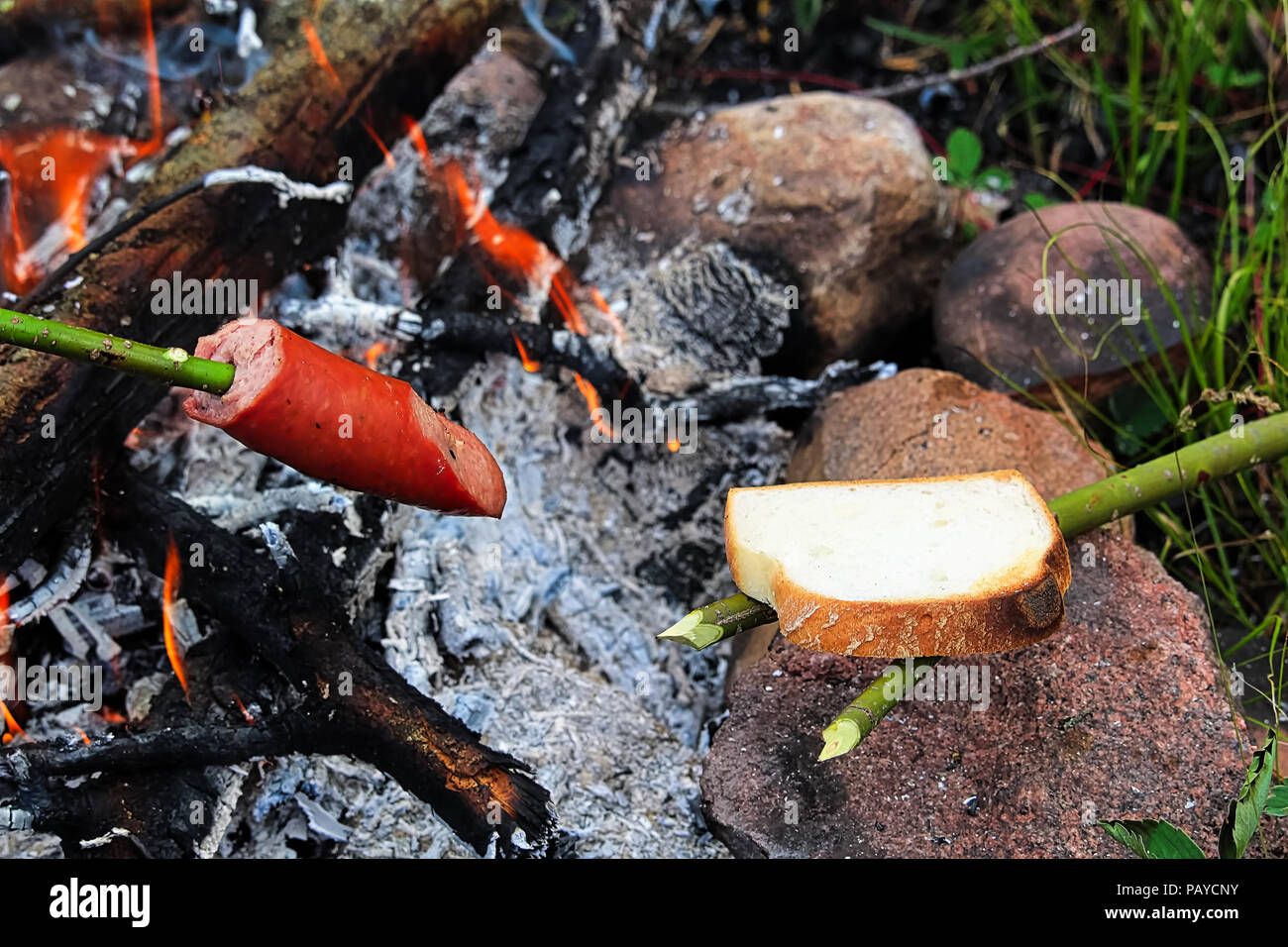 Tostare il pane e salame oltre a un falò Foto Stock