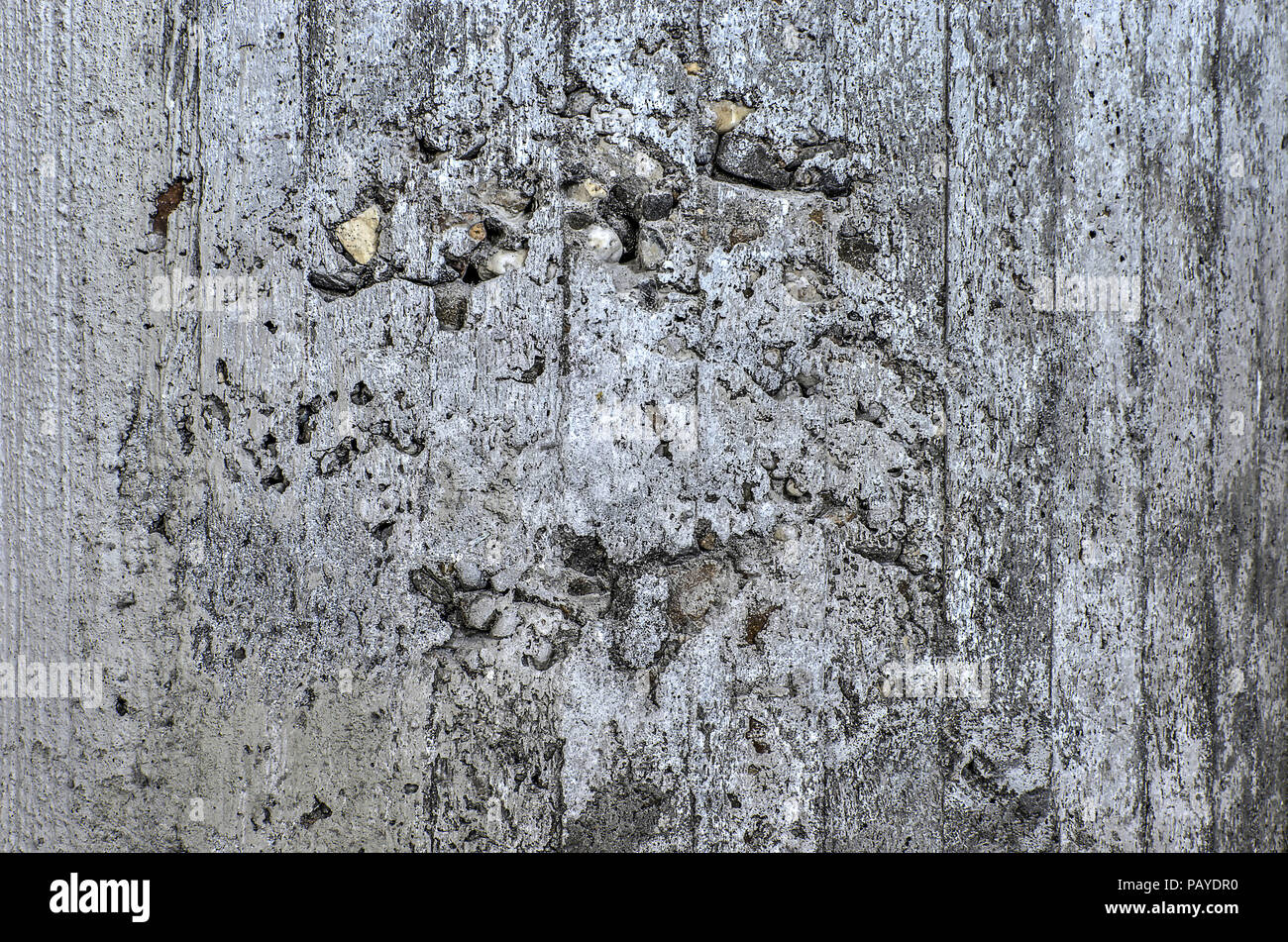 Ruvida la superficie in calcestruzzo con linee verticali del cassero visibile e con fori di rivelare la ghiaia e altri elementi aggregati Foto Stock
