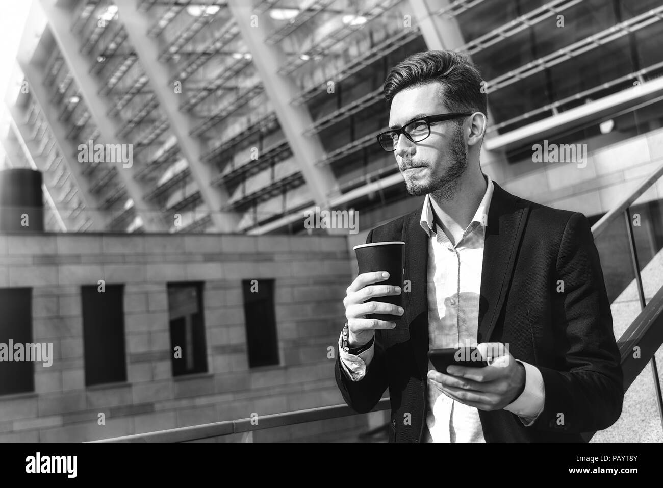 Bel imprenditore di successo in abito elegante stand all'aperto a street nella città con il caffè. Foto Stock