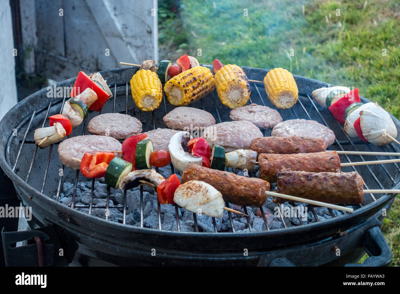 Hamburger, spiedini di agnello e spiedini di verdure per la cottura in un barbecue. Foto Stock