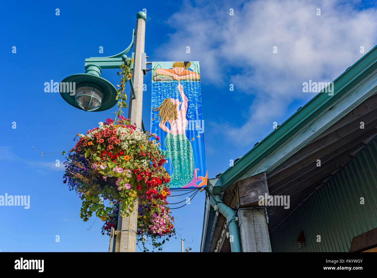 Polo della lampada con cestello pensili e mermaid banner, Harbour Quay, Port Alberni, British Columbia, Canada Foto Stock