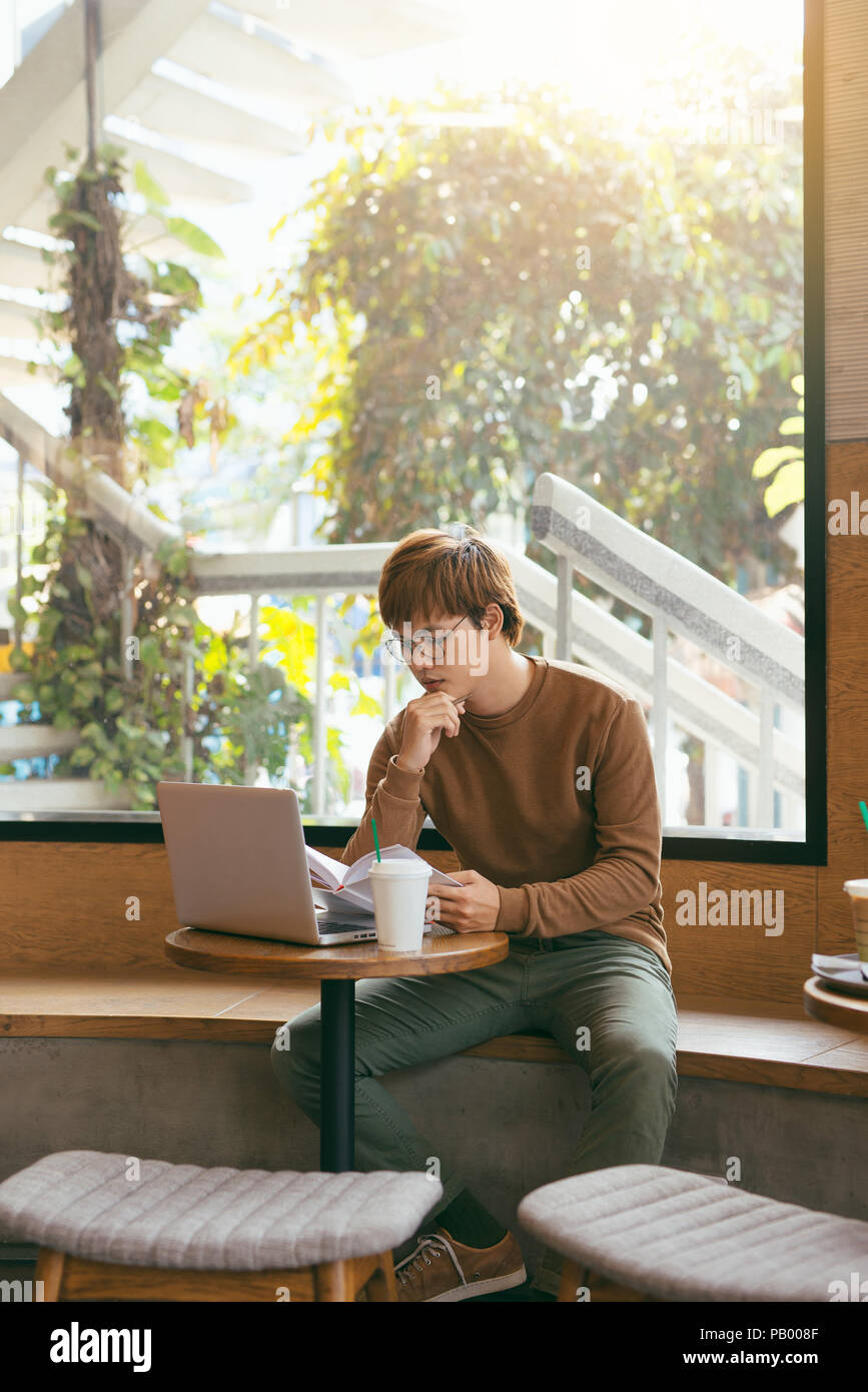 Allegro giornalista maschio nel quartiere alla moda di occhiali felice per il lavoro di finitura su book review rilettura scritto nel testo del notebook prima di chiamare a editor per prese Foto Stock