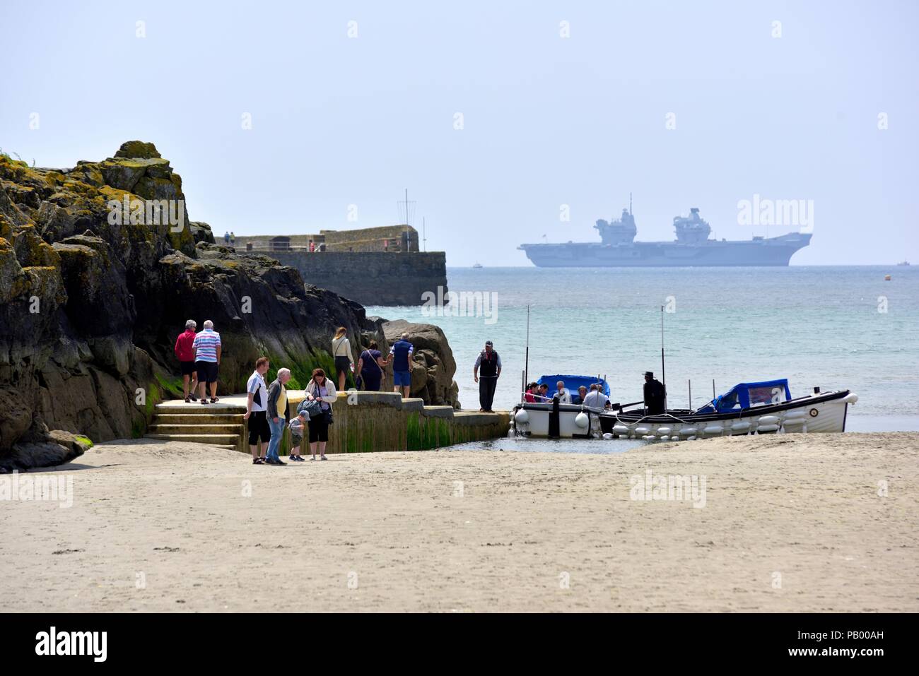 Le imbarcazioni turistiche presso il molo in Marazion con HMS Queen Elizabeth R08 Portaerei in background,Cornwall ,l'Inghilterra,UK Foto Stock