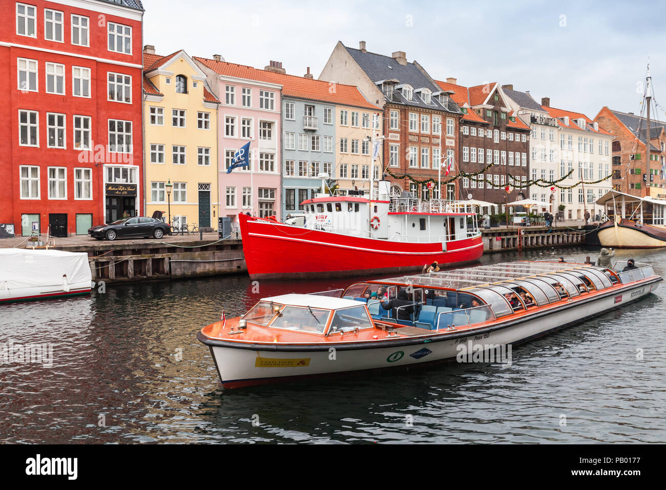 Copenhagen, Danimarca - 10 dicembre 2017: imbarcazione turistica con i passeggeri. Nyhavn o porto nuovo, è un monastero del XVII secolo waterfront, canal e popolare turi Foto Stock Copenhagen, Danimarca - 10 dicembre 2017: imbarcazione turistica con i passeggeri. Nyhavn o porto nuovo, è un monastero del XVII secolo waterfront, canal e popolare turi Foto Stock