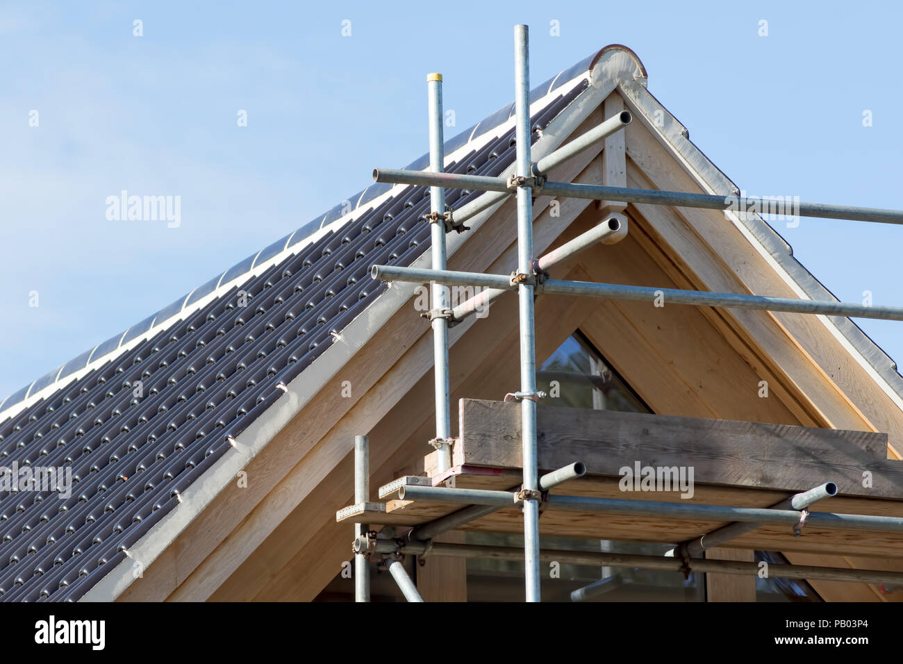 Casa moderna struttura del tetto. Nero curvo di piastrelle di ceramica con un ponteggio sulla parte anteriore di un costoso nuovo costruire casa. Foto Stock