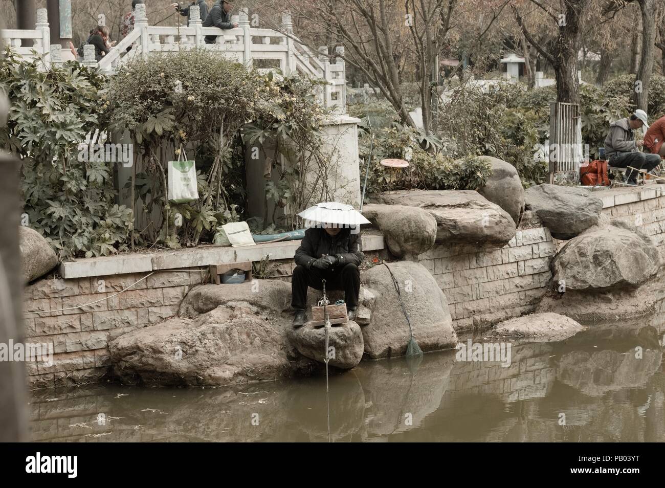 Kunming, Yunnan, Cina - 30 dicembre 2017: una donna è la Pesca nel laghetto di loto Lago Foto Stock
