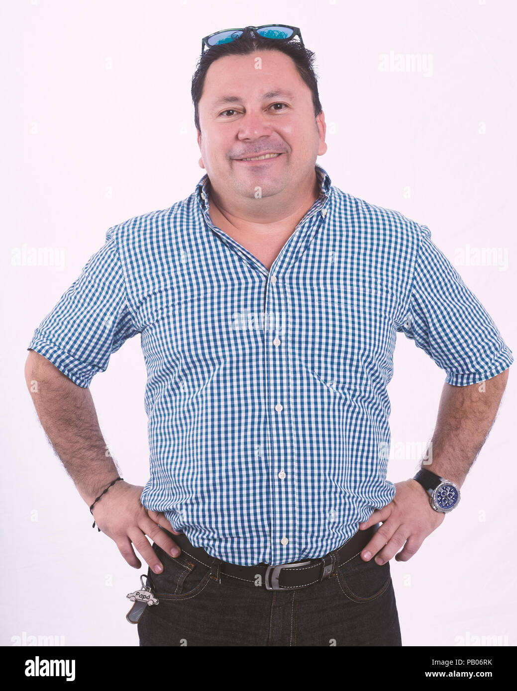 Studio ritratto di un uomo sorridente con bracci sulla vita, e alla ricerca per la fotocamera Foto Stock