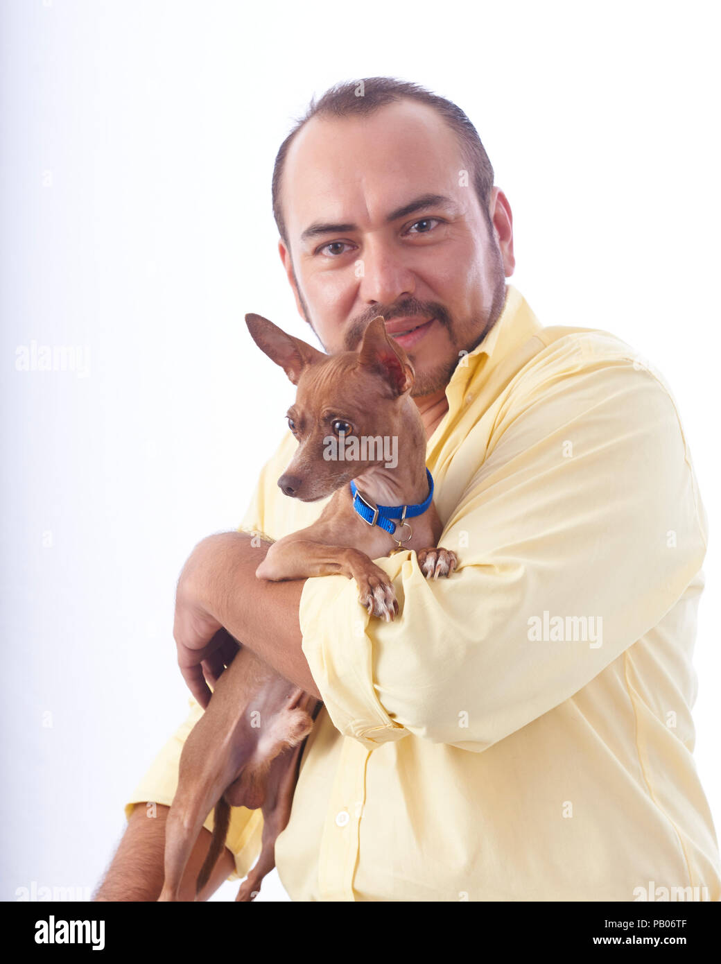 Ritratto in studio su uno sfondo bianco di un uomo in una maglietta gialla, tenendo un chihuahua cane nelle sue braccia Foto Stock