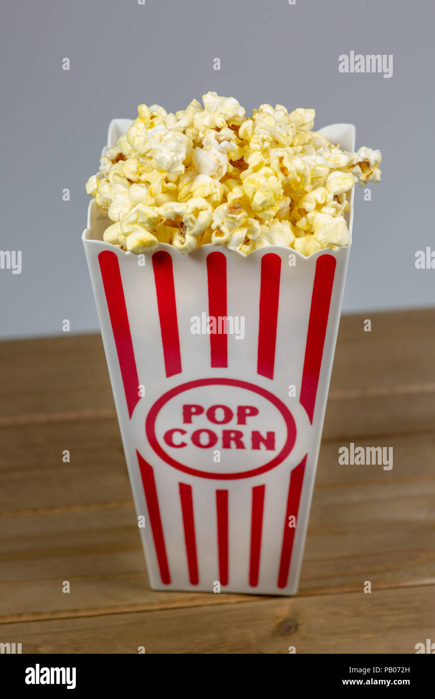 Un rosso spogliato di popcorn piccolo cucchiaio colmo di popcorn su un contatore di bianco Foto Stock