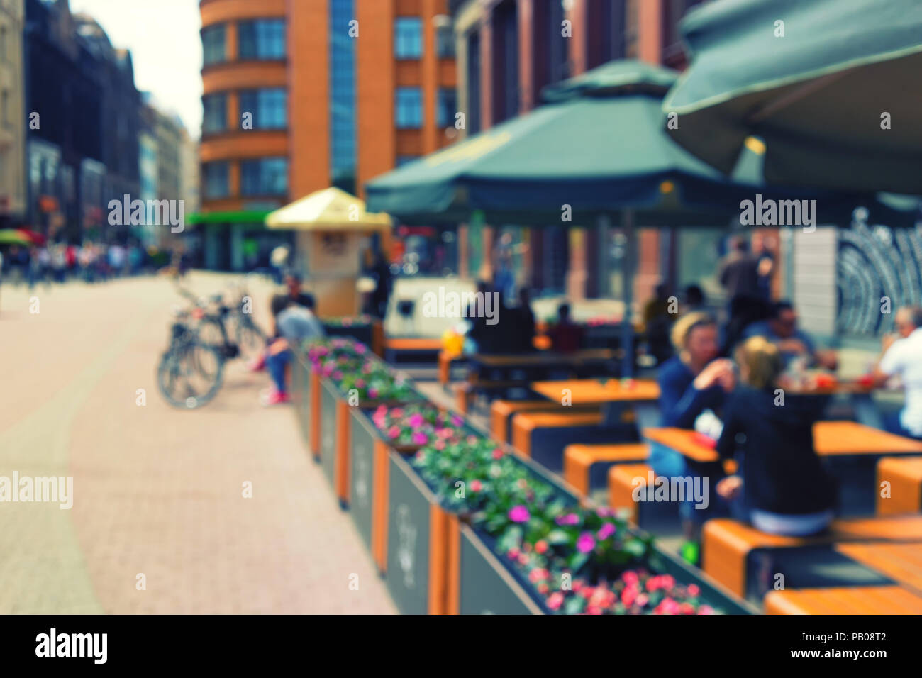 Persone sedersi ai tavoli in estate cafe su una strada nel centro di Riga in una giornata di sole Foto Stock