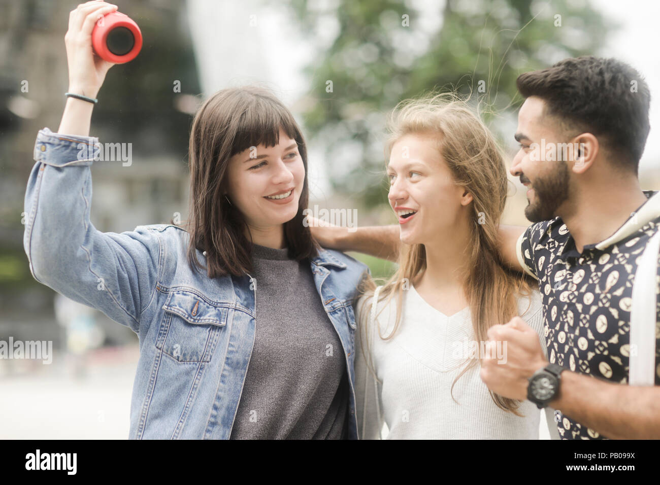 Tre amici con i loro bracci intorno a ogni altro ascolto di musica Foto Stock