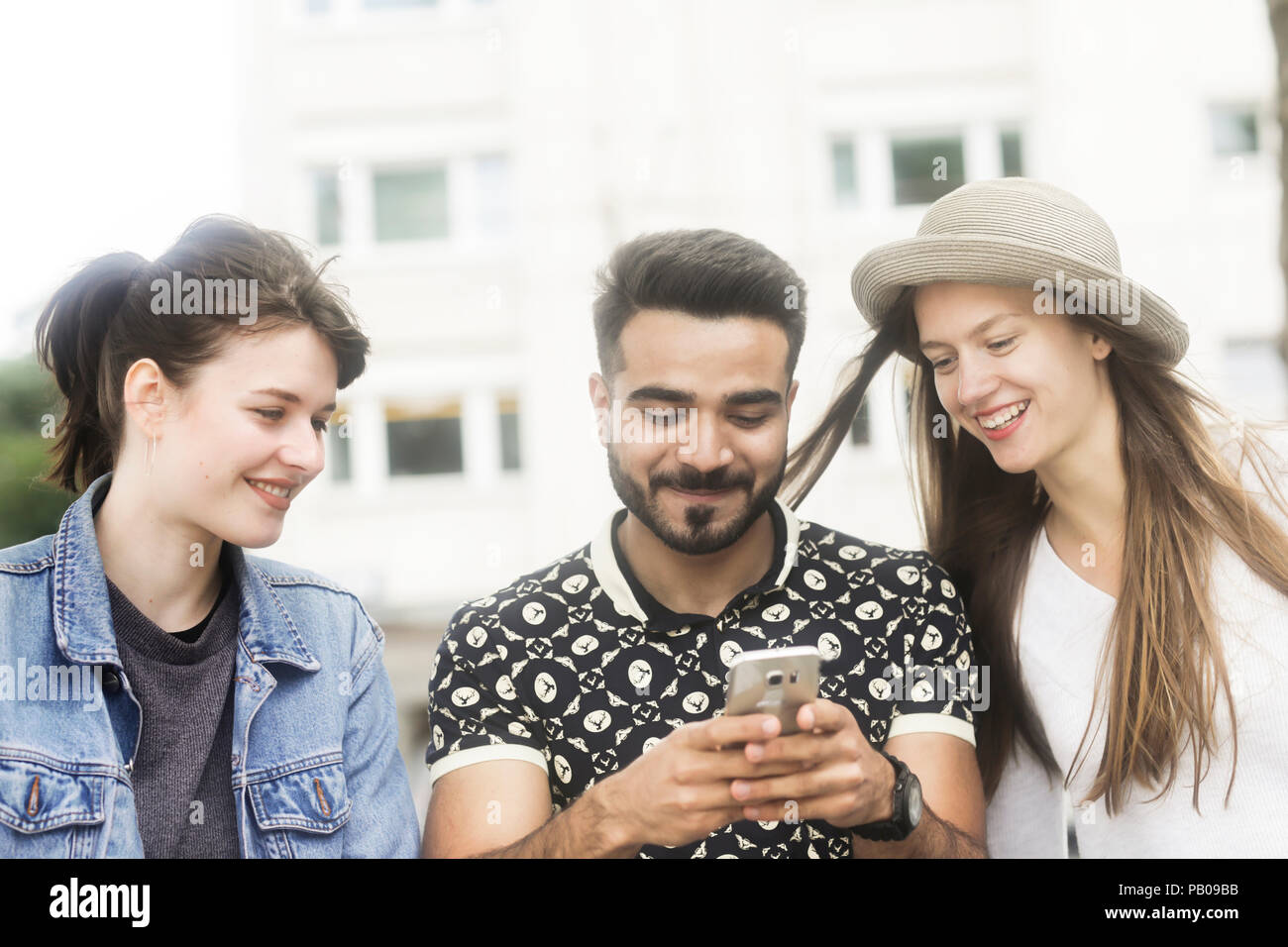 Tre amici alla ricerca di un telefono cellulare Foto Stock