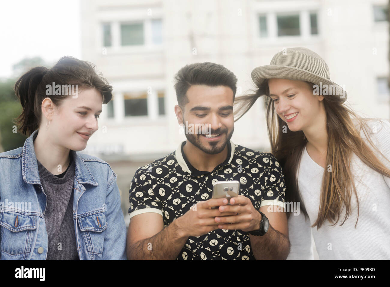 Tre amici alla ricerca di un telefono cellulare Foto Stock