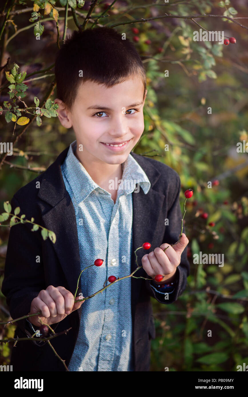 Ritratto di un ragazzo sorridente in piedi da una boccola di rosa canina, Bulgaria Foto Stock