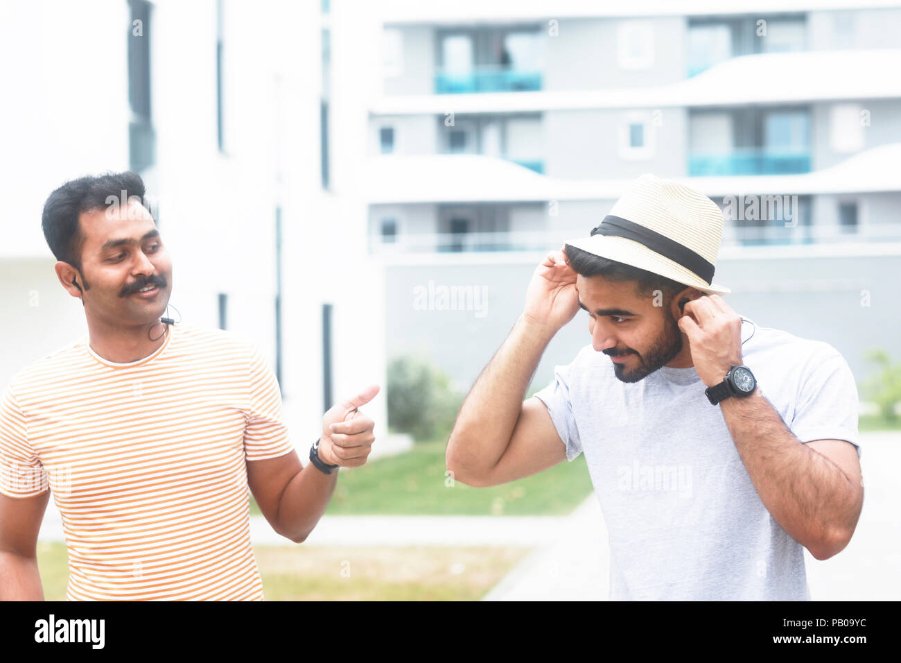 Due uomini in ascolto di musica con gli auricolari wireless Foto Stock