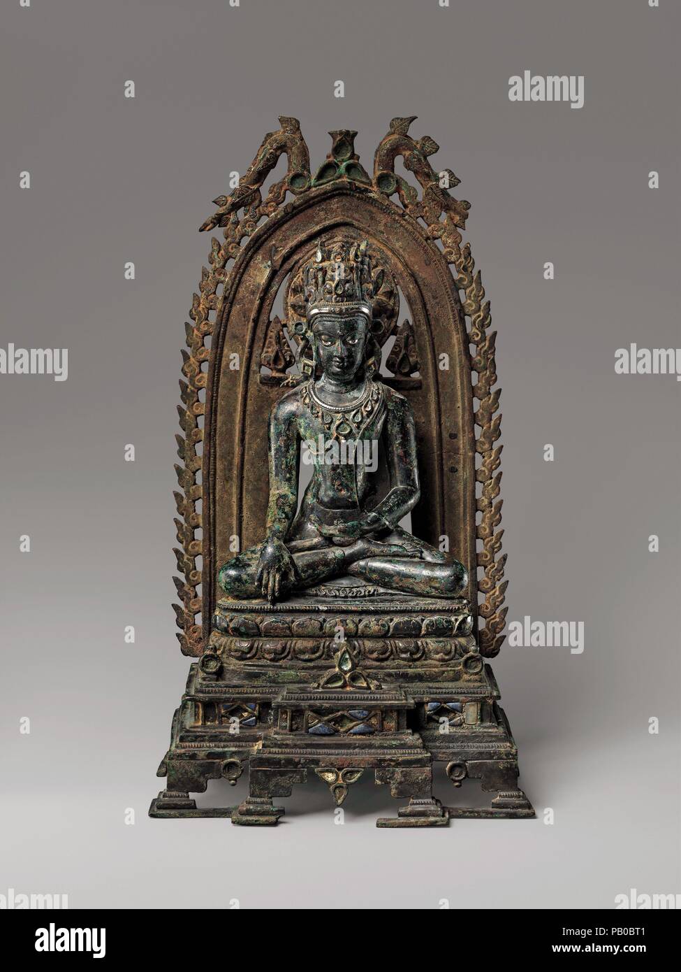 Incoronato il Buddha. Cultura: India (Bihar). Dimensioni: H. 12 5/8 in. (32,1 cm); W. 7 1/8 in. (18,1 cm); D. 5 1/4 in. (13,3 cm); Wt. 7 libbre (7 libbre (3,2 kg). Data: 10th-11secolo. Il Buddha non tocca terra al momento dell'illuminismo. La sua corona, collana, occhi e urna (fronte dot) sono intarsiati con argento; i Flaming mandorla e il trono a gradini erano intarsiato con lapislazzuli e il cristallo di rocca (superstiti vestigia di questi materiali può essere visto sulla base). Museo: Metropolitan Museum of Art di New York, Stati Uniti d'America. Foto Stock