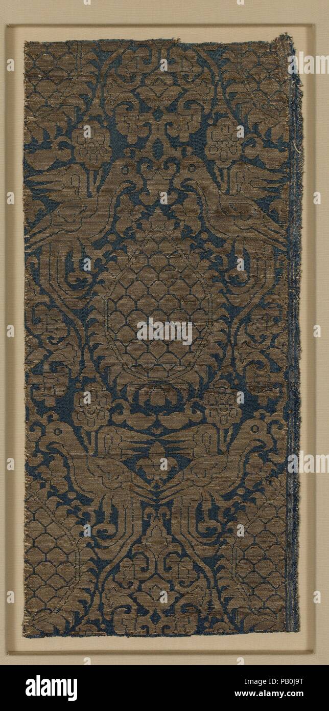 Frammento di tessili. Dimensioni: Tessile: L. 14 a. (35,6 cm) W. 6 1/2 in. (16,5 cm) Monte: L. 18 1/4 in. (46,4 cm) W. 10 7/8 in. (27,6 cm) D. 7/8 in. (2.2 cm). Data: seconda metà XIII-XIV secolo. Opulenti tessili tessuti di seta e fili di oro, denominato "panno dell'oro" era custodito dai mongolo elite e governanti della successiva dinastia Ilkhanide (1256-1353). Il più lussuoso erano oro-su-tessuti dorati, dove entrambi i pattern e lo sfondo sono stati tessuti in diversi tipi di filo d'oro. Questo frammento, esibendo una scintillante configurazione contro un satin blu massa mentre leggermente meno opu Foto Stock