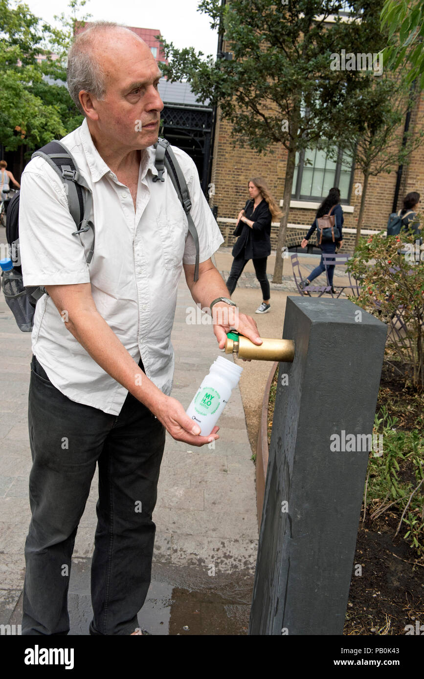 Uomo di riempimento acqua riutilizzabile bottiglia dalla moderna fontana, Kings Cross, London Borough of Camden, Inghilterra Gran Bretagna REGNO UNITO Foto Stock