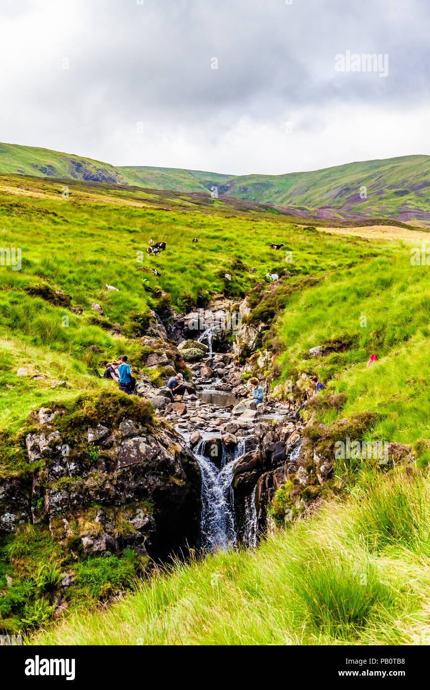 La gente seduta da una cascata nelle colline del National Trust for Scotland grigio del Mare di coda della Riserva Naturale in una calda giornata di luglio. La Scozia, Regno Unito. 2018 Foto Stock