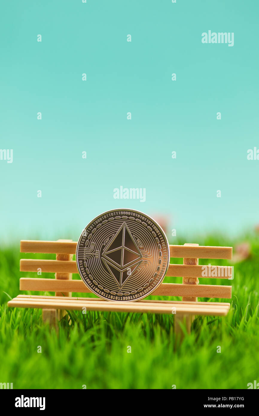 Moneta di etere su una panchina in erba come un concetto di pensione Foto Stock