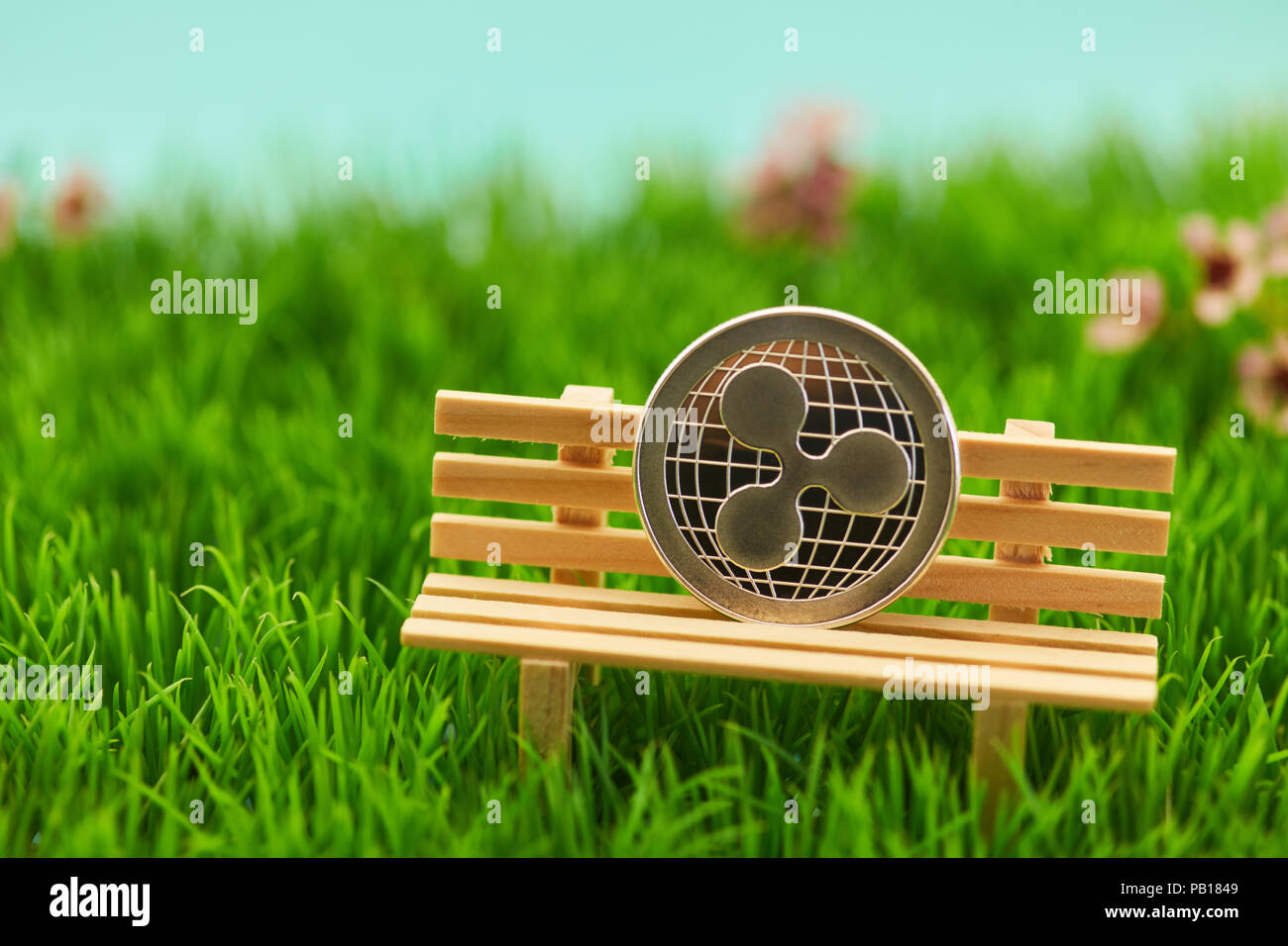 Ripple moneta sul banco in erba di un giardino come un capitolo impianto. Concetto Foto Stock