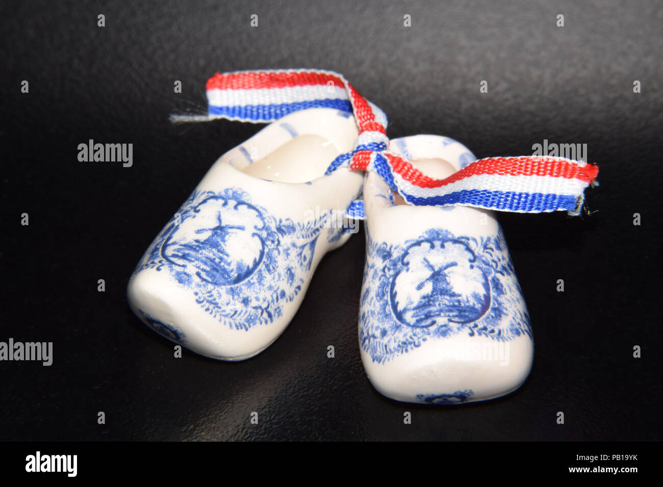 Olandese tradizionale scarpe - zoccoli di legno in porcellain decorate con  il mulino a vento di dettagliati disegni in blu - Isolato su sfondo nero  Foto stock - Alamy