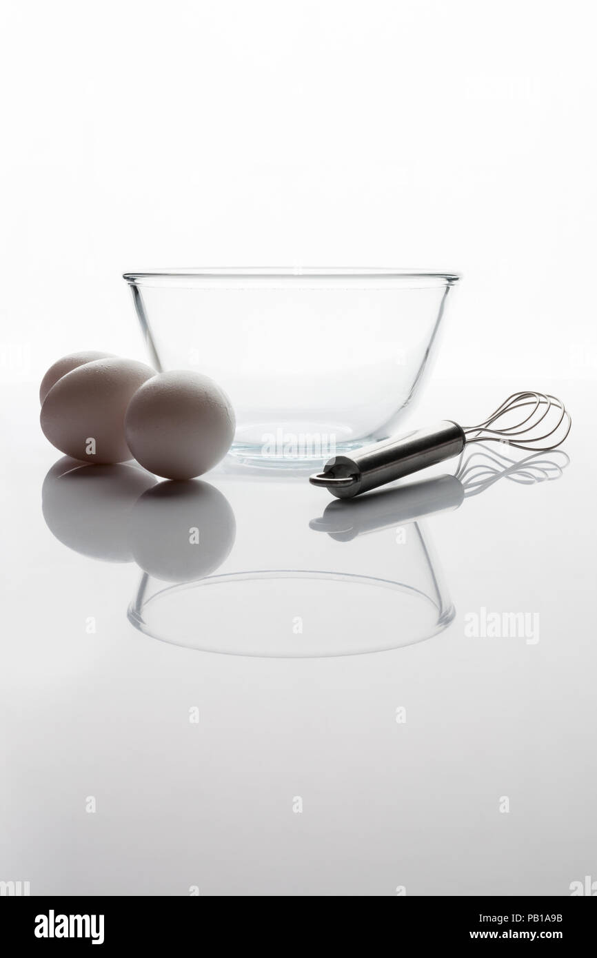 Trasparente come il vetro ciotola con baffo di metallo e tre le uova bianche a parte la vista laterale con verticale di riflessione Foto Stock