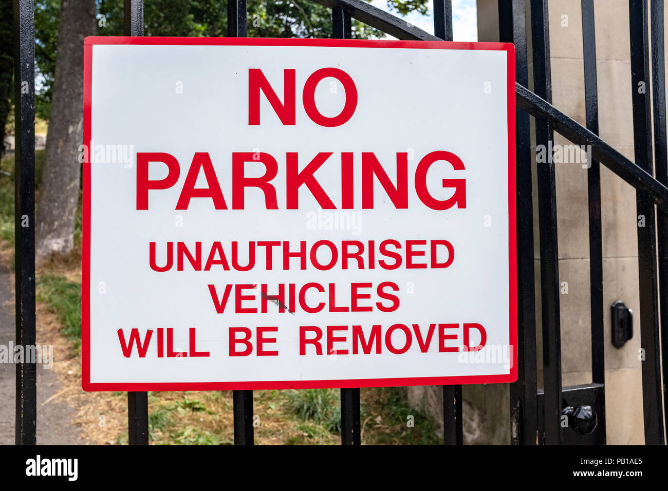Rosso e bianco, nessun parcheggio veicoli non autorizzati saranno rimossi segno su nero ringhiere in ferro. Foto Stock