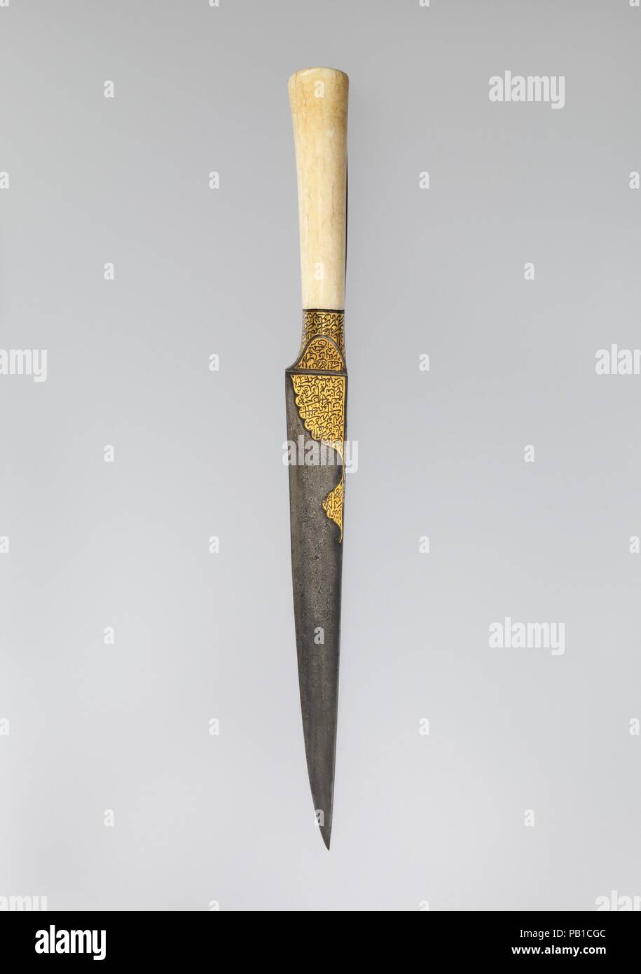 Coltello con il manico di ebano e Qur'Anic iscrizioni. Dimensioni: L. 14 1/16 in. (35,7 cm) W. 1 1/4 in. (3.2 cm). Data: inizio del XIX secolo. Questo pugnale è stata incisa con Qur'Anic passaggi sul forte della lama, come pure sul manico di avorio. L'inclusione di sante parole su questo oggetto impregnandolo con proprietà talismanic, credeva di offrire protezione e scongiurare il male. Il più efficace talismanic oggetti sono quelli che sono inscritte con preghiere che evocano il nome di Dio, il profeta Maometto e dei suoi compagni. 'Damascus' o 'annaffiato' acciaio si riferisce a pale come questo tha Foto Stock