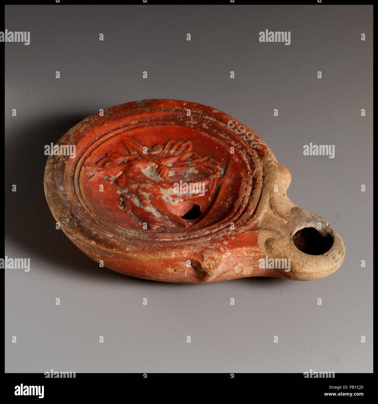 Olio di terracotta con lampada. Cultura: Romano. Dimensioni: complessivo: 1 x 3 3/8 in. (2,5 x 8,6 cm). Data: ca. A.D. 40-100. Loeschcke Tipo 4. Stampo-fatta. Discus: Aktaion, stando in piedi alla parte anteriore, rivolto verso sinistra, di essere attaccato da un cane a sinistra e tenendo una lancia in mano sinistra; tutti su una linea di massa attraverso il basso dei Discus. Museo: Metropolitan Museum of Art di New York, Stati Uniti d'America. Foto Stock