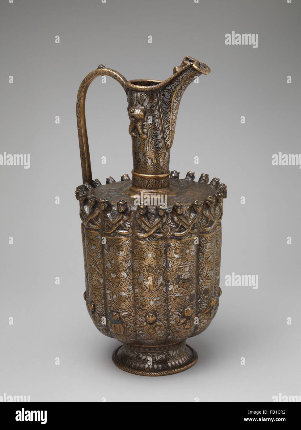 Ewer. Dimensioni: H. 15 3/4 in. (40 cm) Diam 7 1/2 in. (19,1 cm). Data: ca. 1180-1210. Questo ewer proviene da un gruppo di argento-ottone intarsiato navi di forma simile e dimensioni e decorate con una varietà di immagini. Mentre la maggior parte degli esempi hanno lati scanalati e repoussé lions sul loro collo, incoronato arpie sulla spalla di questo pezzo e le immagini astrologiche sul suo corpo esaltare il buon auspicio del suo ornamento. Impostare in medaglioni di vitigni di ritorcitura terminante in conigli' teste, ogni segno zodiacale appare con la sua sentenza il pianeta, potenziando il suo messaggio cosmico. Museo: Metropolitan Museum Foto Stock