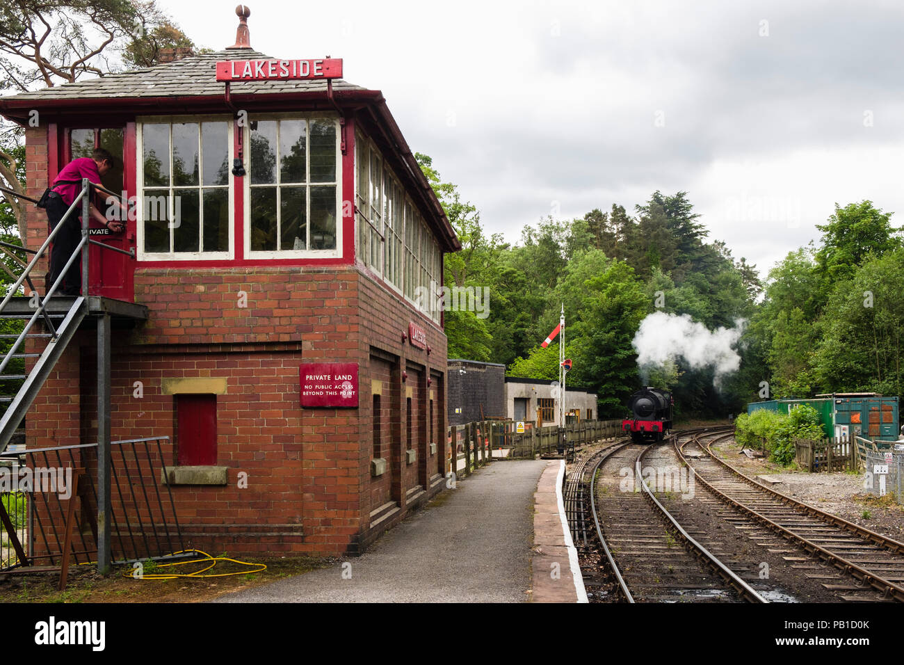 Treno a vapore il motore si avvicina e Lakeside Haverthwaite stazione ferroviaria la casella segnale nel Parco Nazionale del Distretto dei Laghi. Lakeside, Cumbria, England, Regno Unito Foto Stock