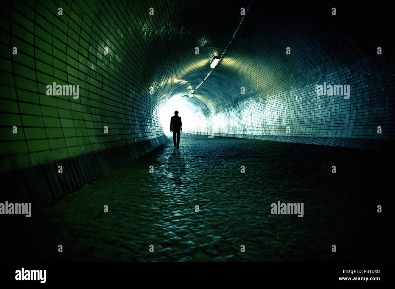 Uomo a camminare sotto un tunnel verso l'uscita - immagine per la copertina del libro Foto Stock