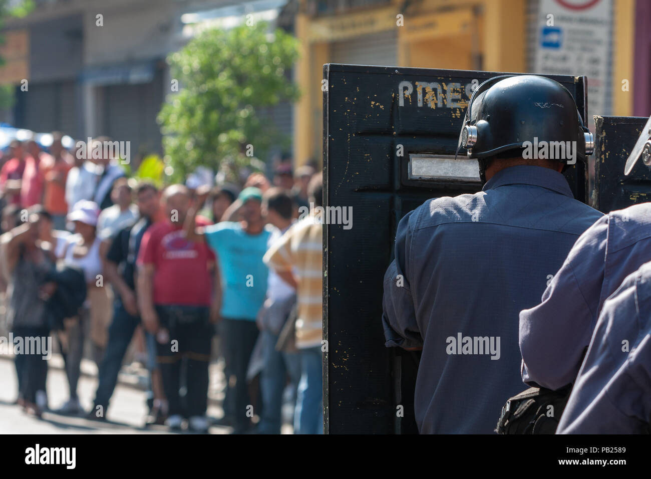 Una polizia tumulto guarda da dietro lo scudo mentre lui e gli altri si trovano di fronte a dimostranti in vista durante una protesta dei venditori ambulanti, a Sao Paulo, Brasile Foto Stock