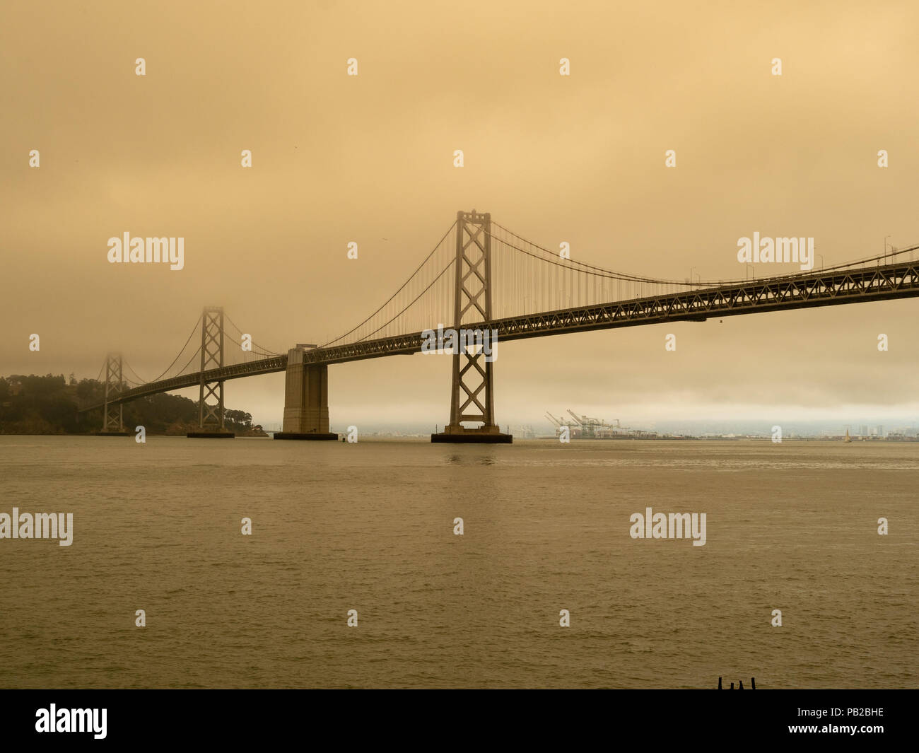 Il Bay Bridge circondato dallo smog da incendi nelle vicinanze. Aria pulita può essere visto in lontananza al Porto di Oakland Foto Stock