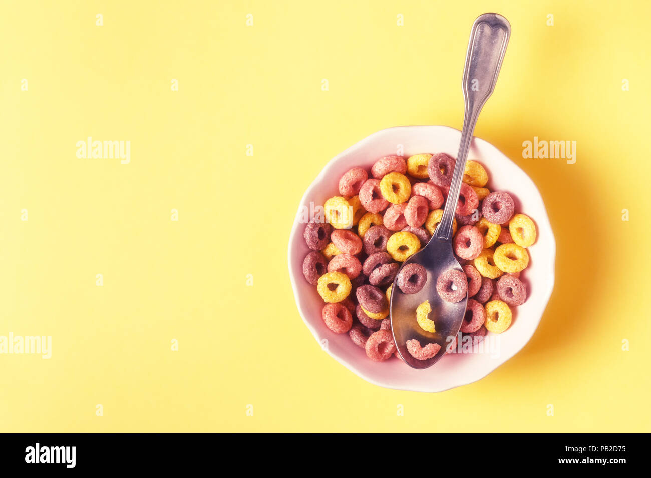 Una sana colazione con granella colorata anelli e cucchiaio con faccia buffa. Foto Stock