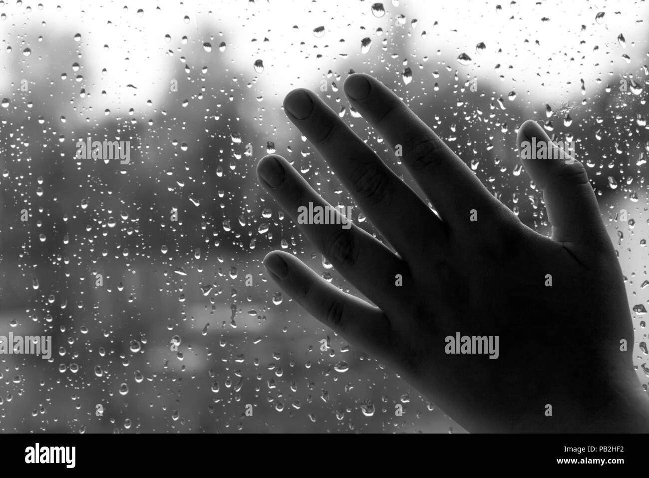 Bambino la mano sul vetro del finestrino in gocce di pioggia Foto Stock