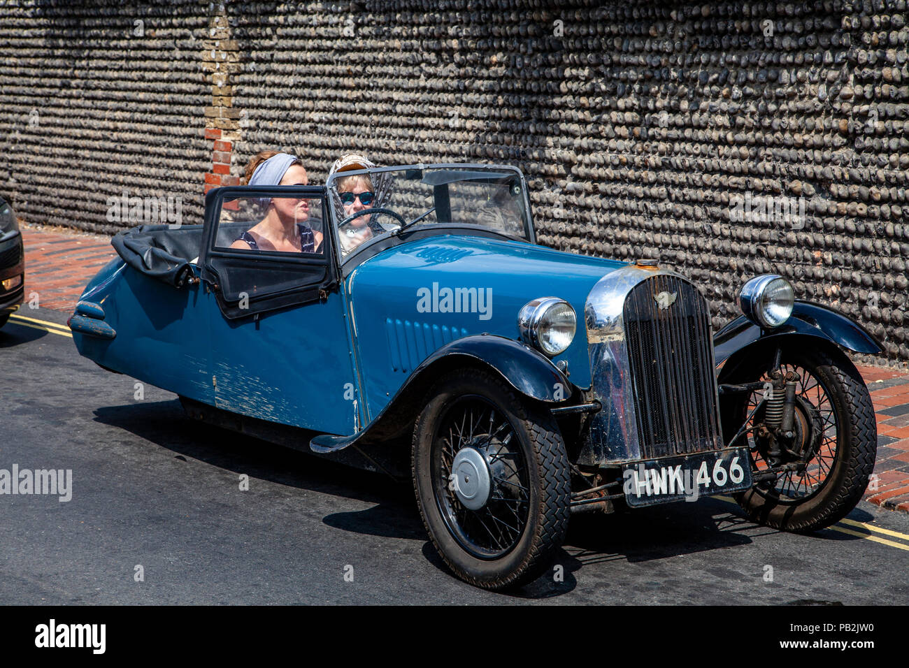 Due donne sedute nel traffico in un vecchio a tre ruote auto, Rottingdean, Sussex, Regno Unito Foto Stock