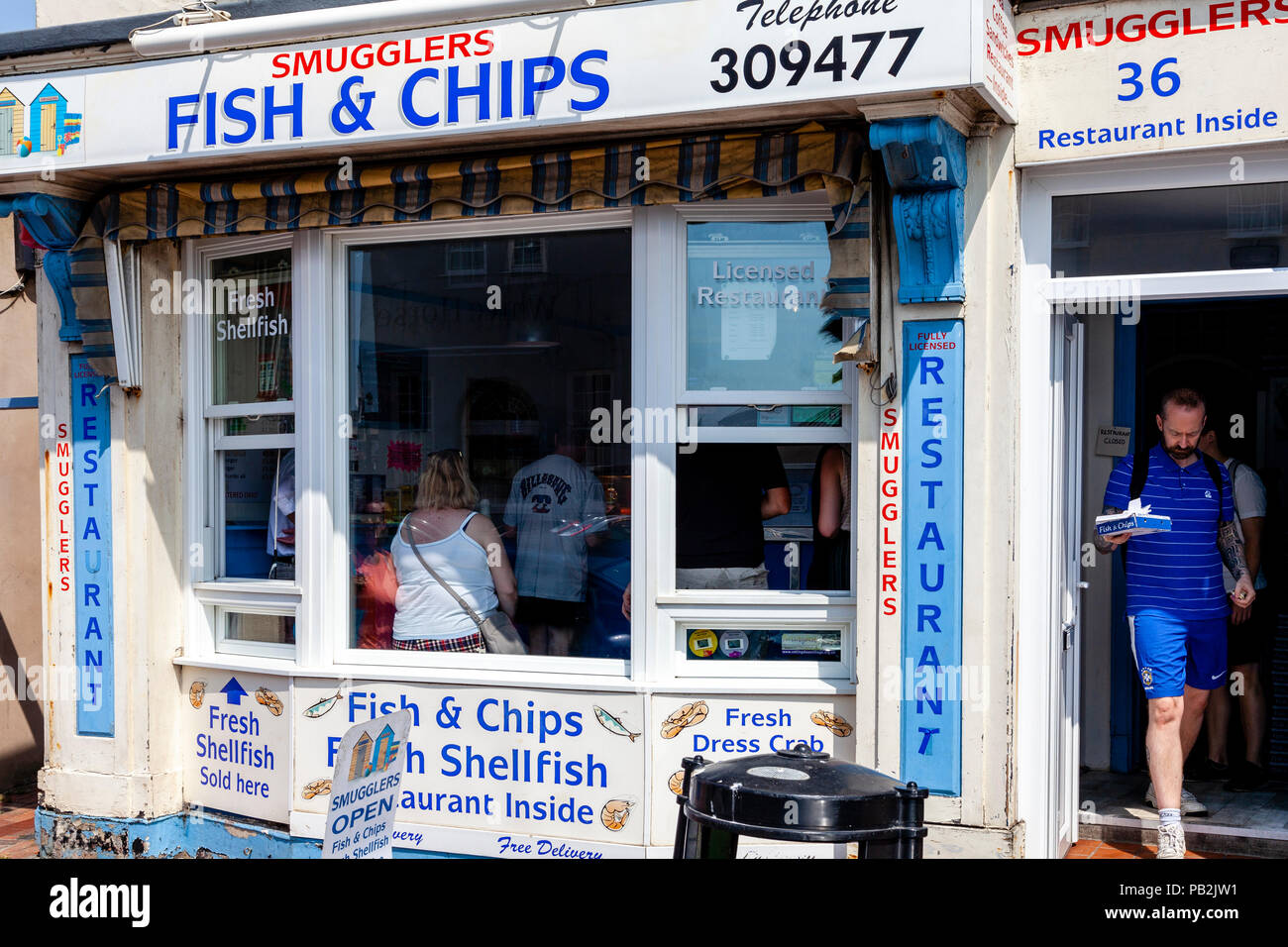 Un uomo lascia il tradizionale pesce e negozio di chip con una scatola di pesce e patatine, Rottingdean, Sussex, Regno Unito Foto Stock