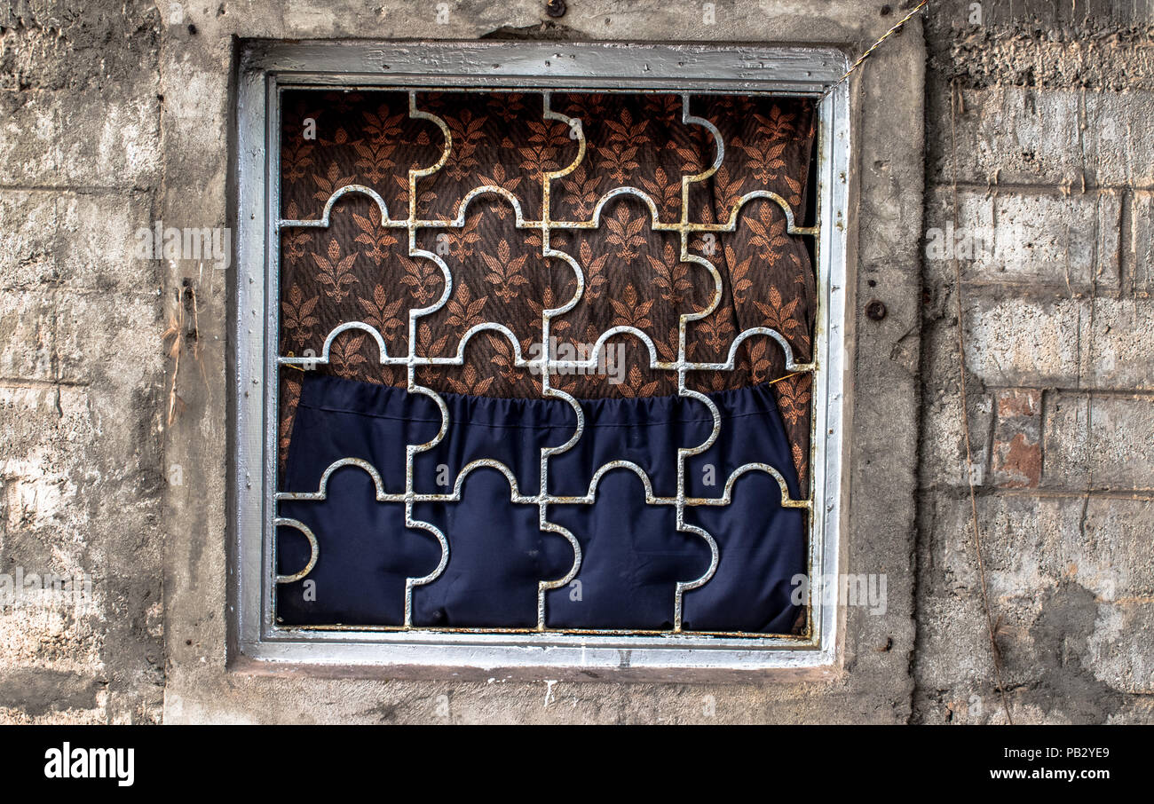 Tradizionale, finestra artistiche costituite da barre di ferro e legno in una classe media villaggio indiano famiglia, utilizzando diverse sfumature di vestiti vecchi come le tende Foto Stock