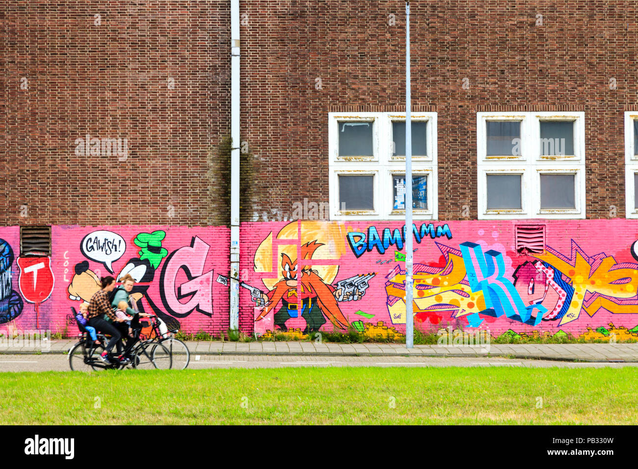 Pedalando attraverso una parete ricoperta di graffiti in NDSM werf, Amdock, Amsterdam, Paesi Bassi Foto Stock