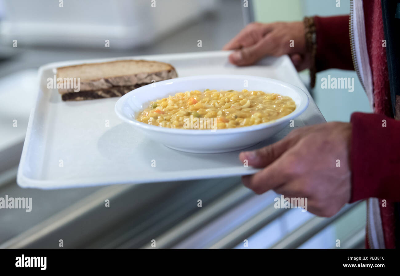 Monaco di Baviera, Germania. 26 Luglio, 2018. Una persona senza dimora preleva una piastra con zuppa al contatore alimentare del San Bonifaz senzatetto Shelter. Il Primo Ministro bavarese Soeder visitato i senza dimora servizio di aiuto per scoprire ciò che aiutano le persone senza un indirizzo permanente necessità e come la loro vita può essere migliorata. Credito: Sven Hoppe/dpa/Alamy Live News Foto Stock