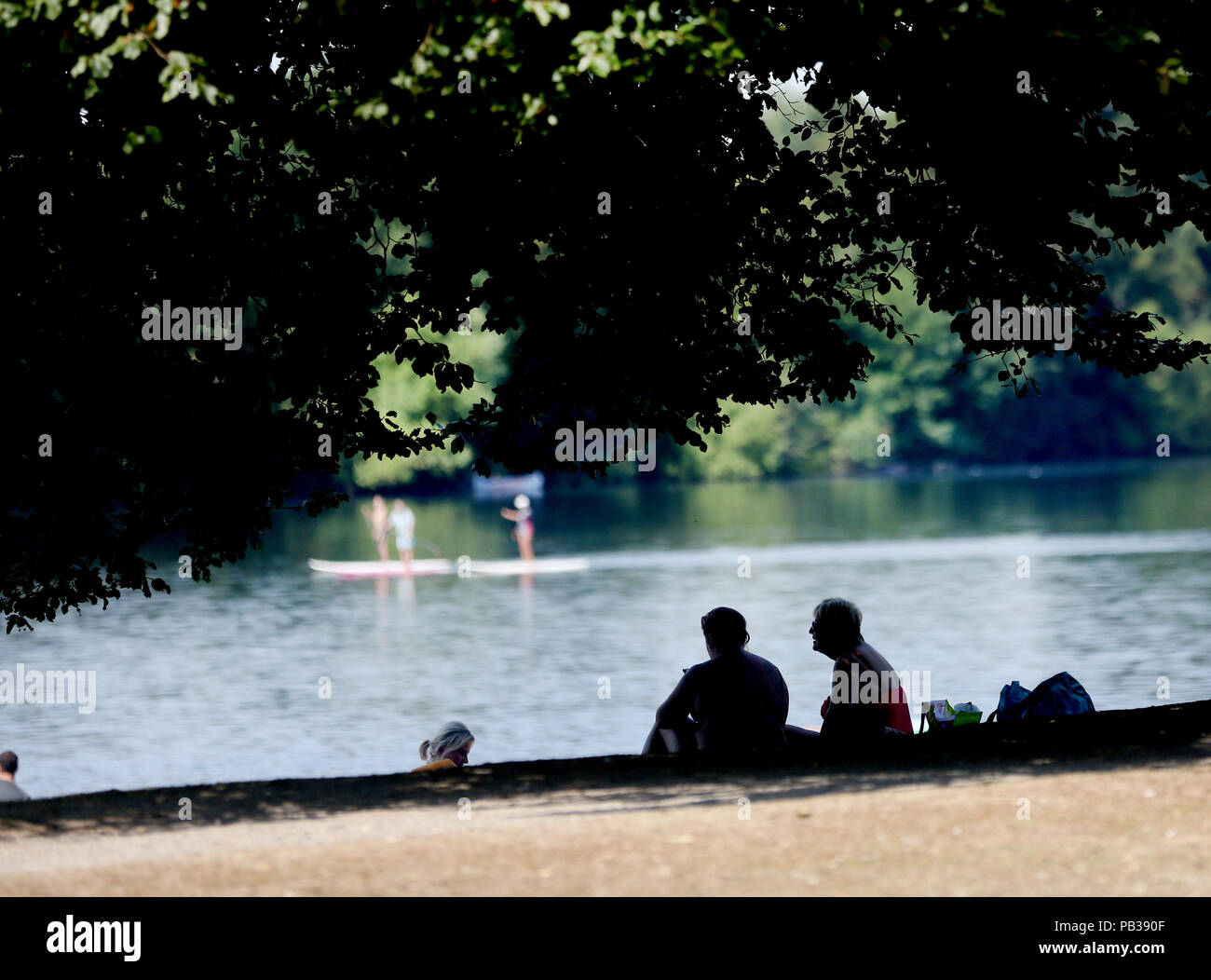 26 luglio 2018, Germania, Duisburg: nella fresca ombra di un grande albero, due donne trascorrono il loro tempo libero presso il lago Masurian dei sei laghi. Foto: Roland Weihrauch/dpa Foto Stock