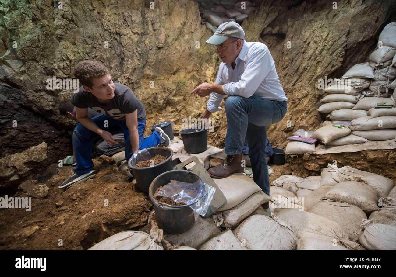 Schelklingen, Germania. 26 Luglio, 2018. L archeologo Nicholas Conard (r) parla di un'archeologia studente nella zona di scavo della grotta "Hohle Fels". A 44 cm lungo mammoth osso con varie marcature è stata scoperta nella grotta "Hohle Fels" sul Swabian Alb. La nervatura ha due righe di marcature che puzzle ricercatori presso l'Università di Tubinga. Credito: Marijan Murat/dpa/Alamy Live News Foto Stock