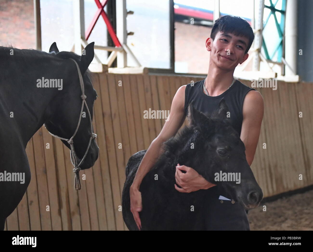 (180726) -- NANCHANG, luglio 26, 2018 (Xinhua) -- Zhou Jian, uno studente di sole scuola di equitazione, detiene un pony nelle sue braccia in Yihuang contea di Fuzhou, Cina orientale della provincia di Jiangxi, 22 maggio 2018. Ippica non era stata mai sentito parlare di in Yihuang, una contea agricola in Cina orientale della provincia di Jiangxi, fino a quando il sole Scuola di Equitazione cominciò a reclutare adolescenti rurale nel 2015. Finora, la maggior parte dei 90 studenti stanno lavorando o che aspirano a lavorare nel club di equitazione in Cina il più grande città come Pechino, Shanghai e Hangzhou. (Xinhua/Zhou Mi) (mm) Foto Stock