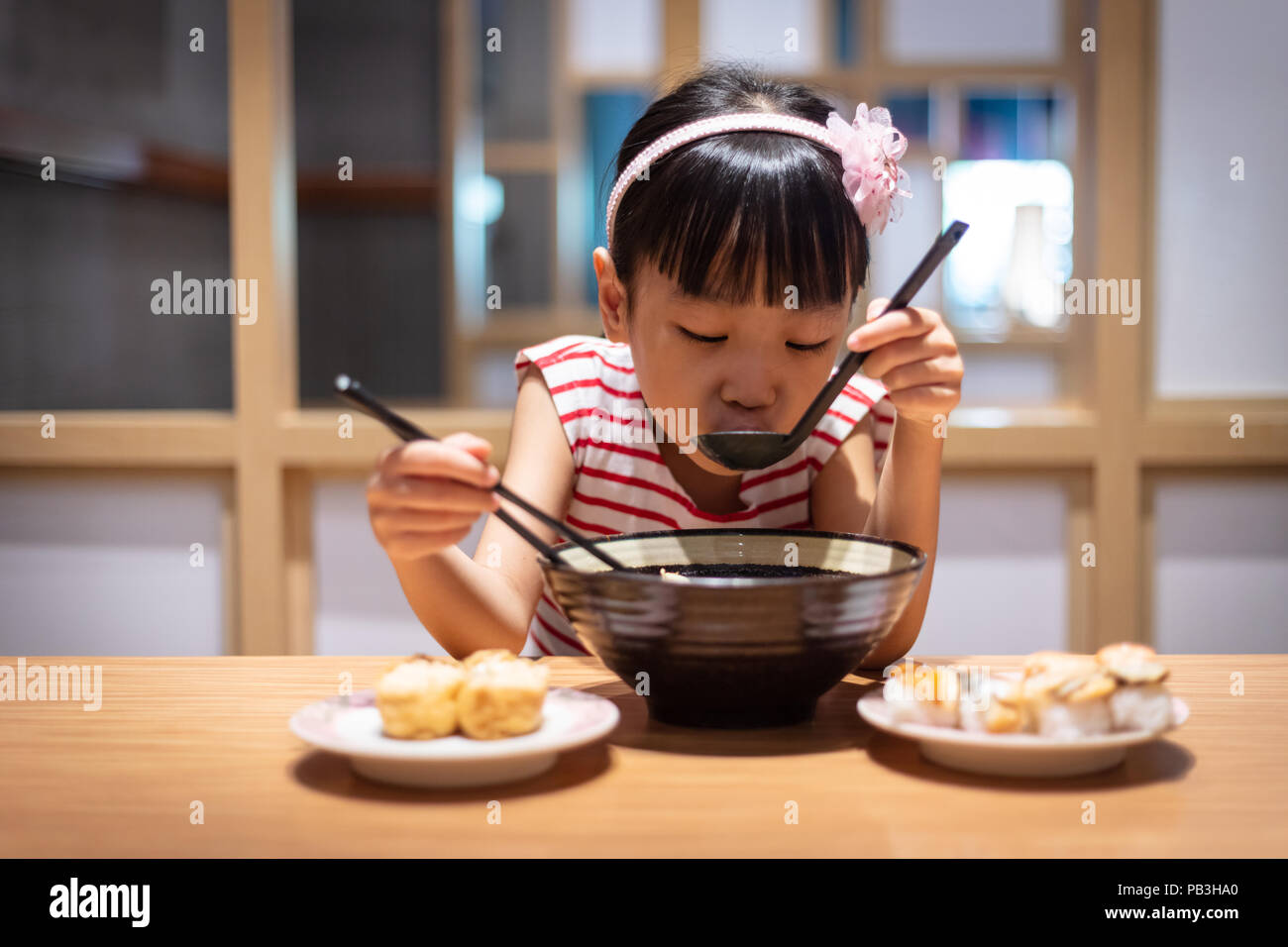 Asian poco ragazza cinese di mangiare spaghetti ramen presso un ristorante giapponese Foto Stock
